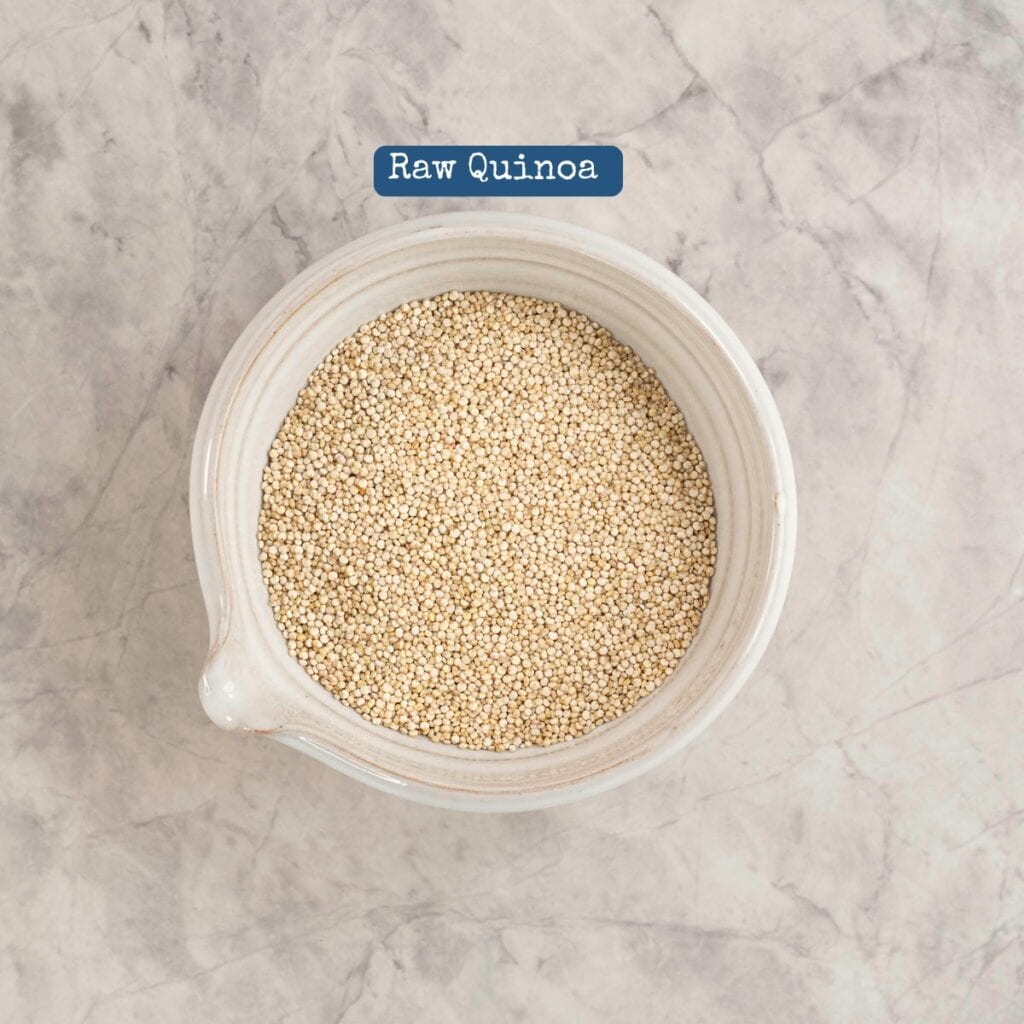 Bowl on marble bench top with raw quinoa inside, with text box above "Raw Quinoa".