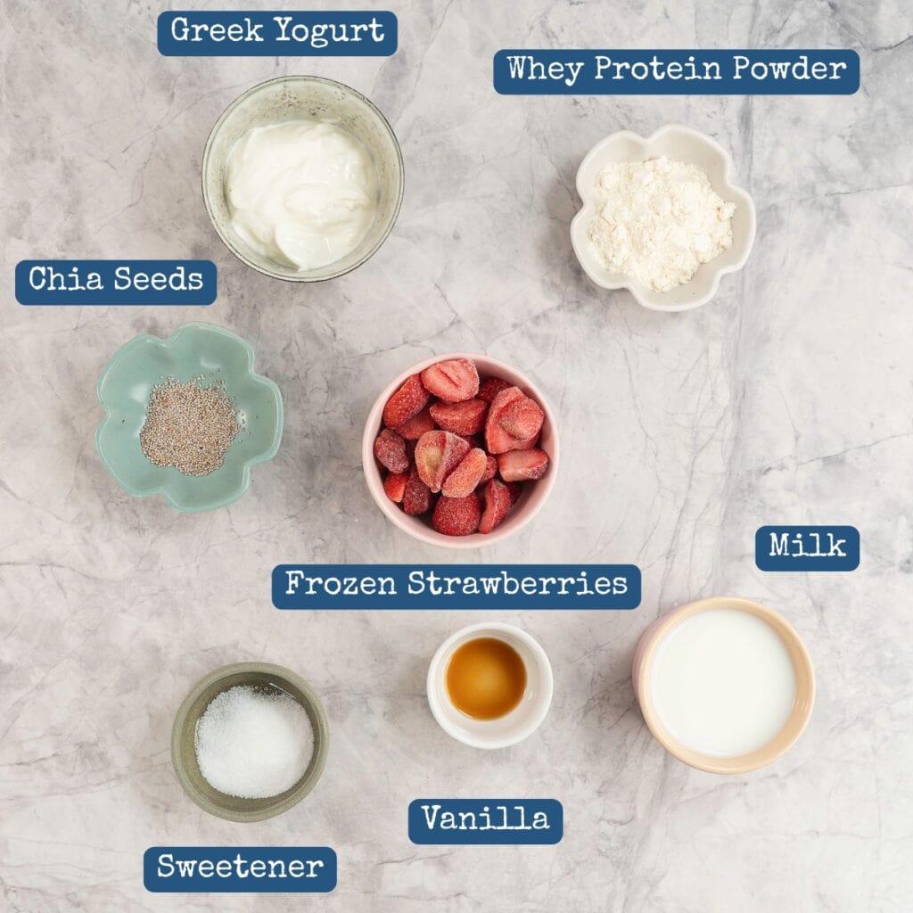 Ingredients for strawberry protein shake on marble benchtop with text overlay.
