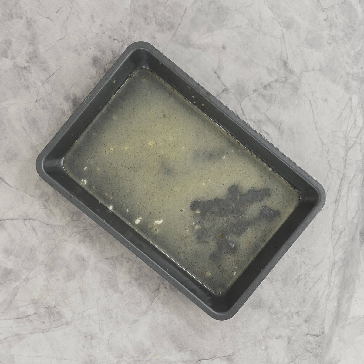 Rectangle baking tray with residue of French toast mixture left inside.
