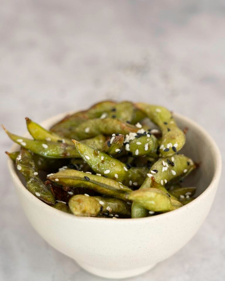 A bowl of edamame pods topped with seasoned black and white sesame.