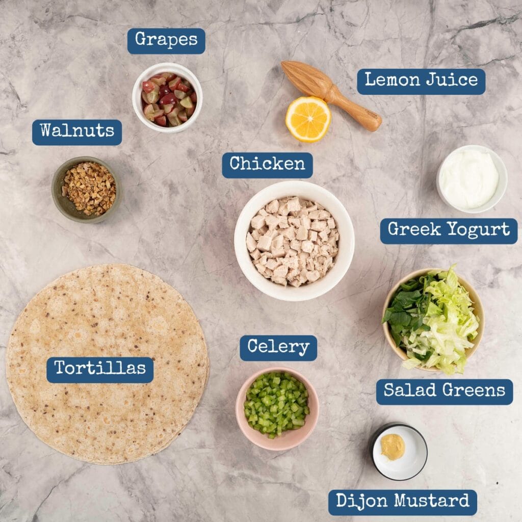 The ingredients to make chicken salad wrap in bowls laid out on a counter top. 