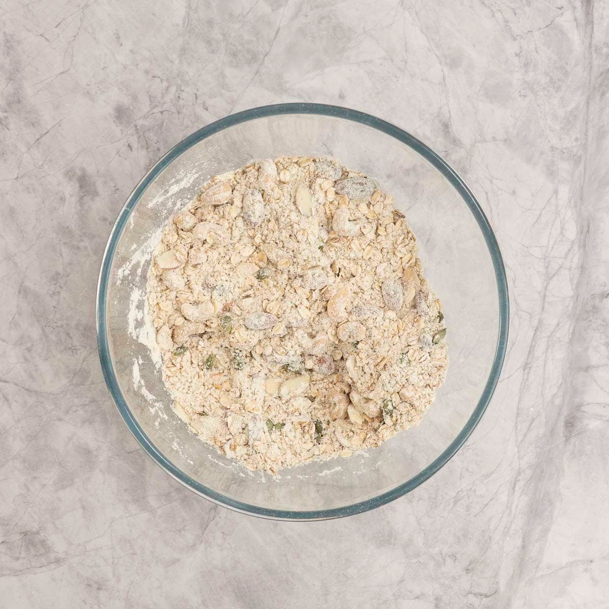 Dry ingredients for granola inside a large glass bowl.