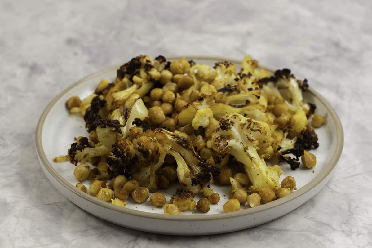 Dinner plate on marble bench top with roasted chickpeas and cauliflower.