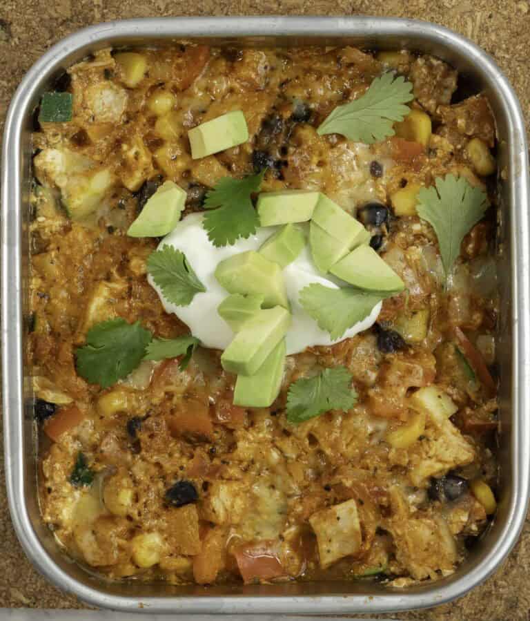 Microwaved enchilada with hot melty cheese sour cream, avocado and coriander leaves on top.