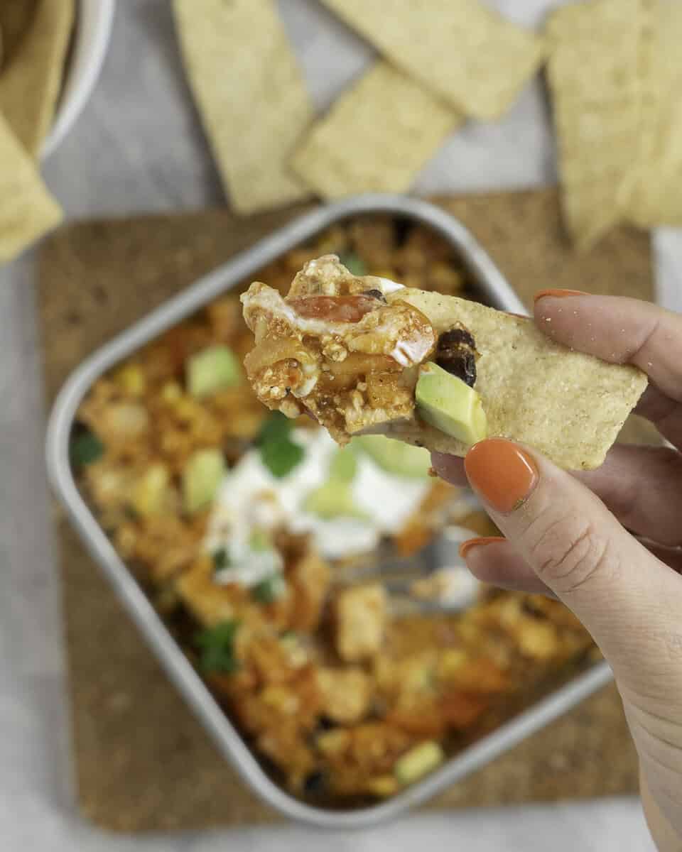 Enchilada filling being scooped up on a corn tortilla strip. 