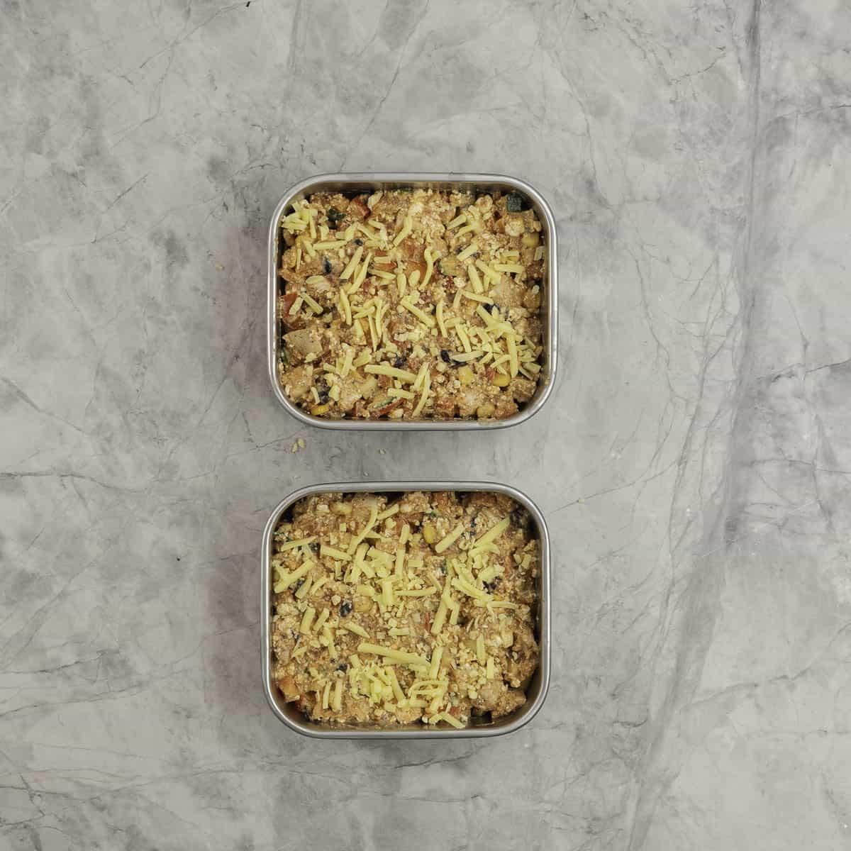 Protein Chicken enchilada mix portioned into stainless steel microwaveable square containers with cheese on the top. 