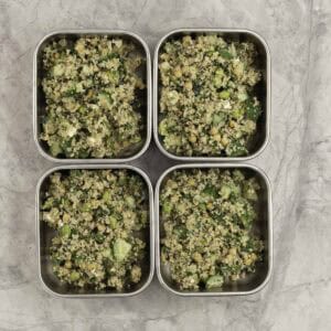Four stainless steel rectangle containers with divided portions of salad inside.