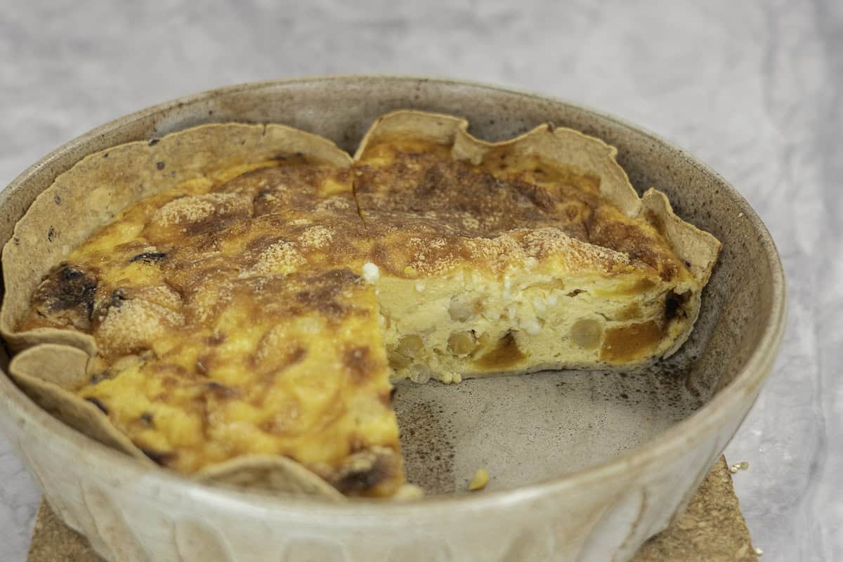 A baking dish with three quarters of a quiche inside.