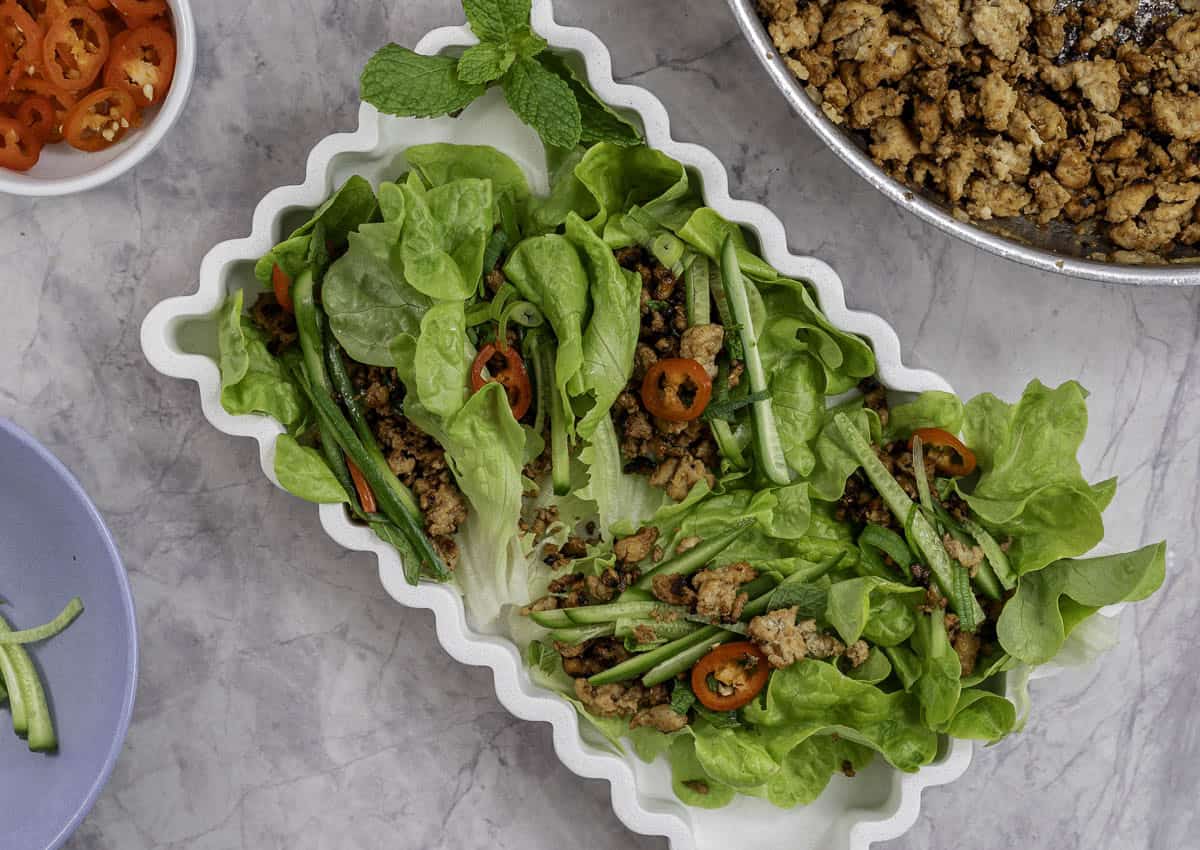 White dish on benchtop with lettuce wraps with fillings inside.