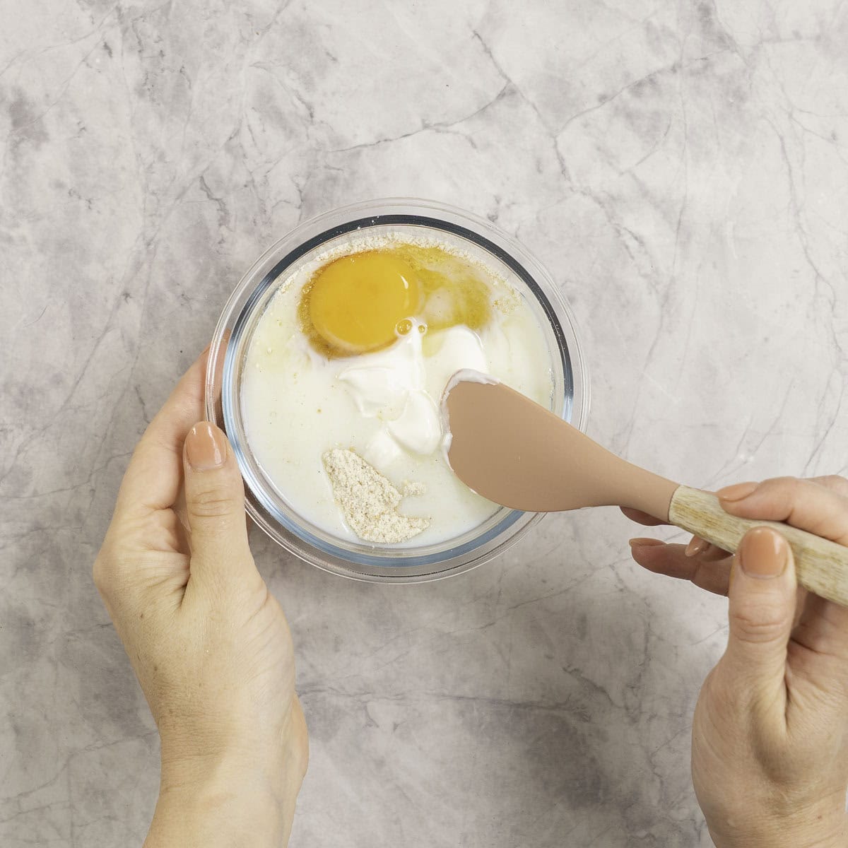 Egg, milk and yogurt added into dry ingredients in small glass ramekin.