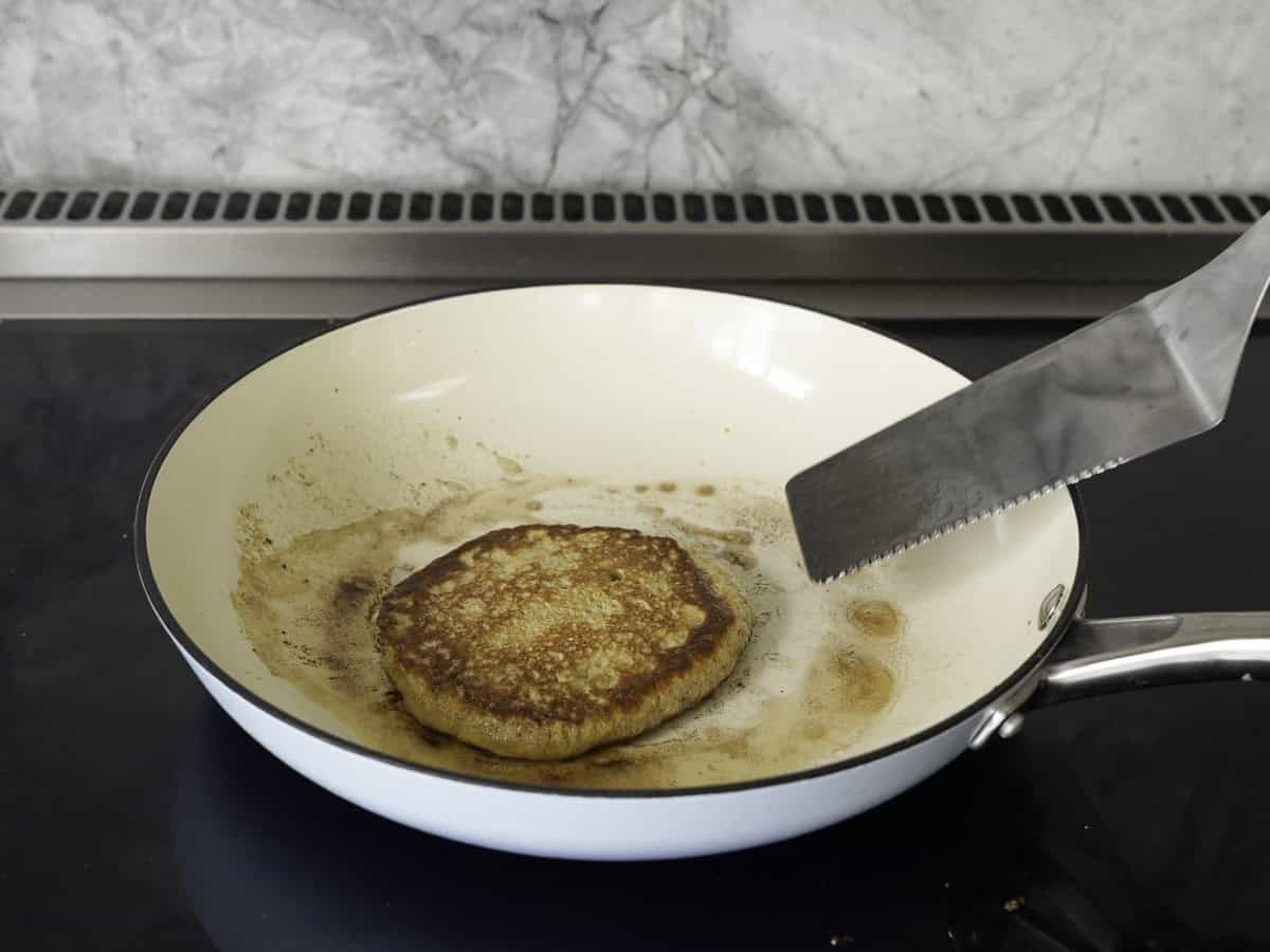 A golden cooked pancake in the bottom of a greased blue pancake pan.