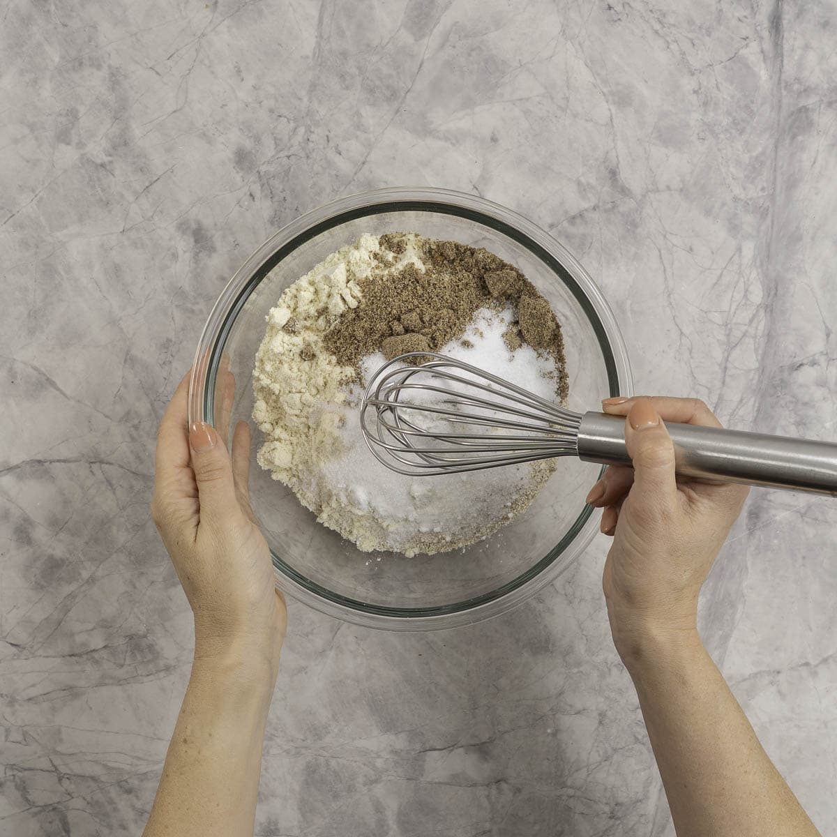 Dry pancake ingredients in a large glass bowl being whisked.