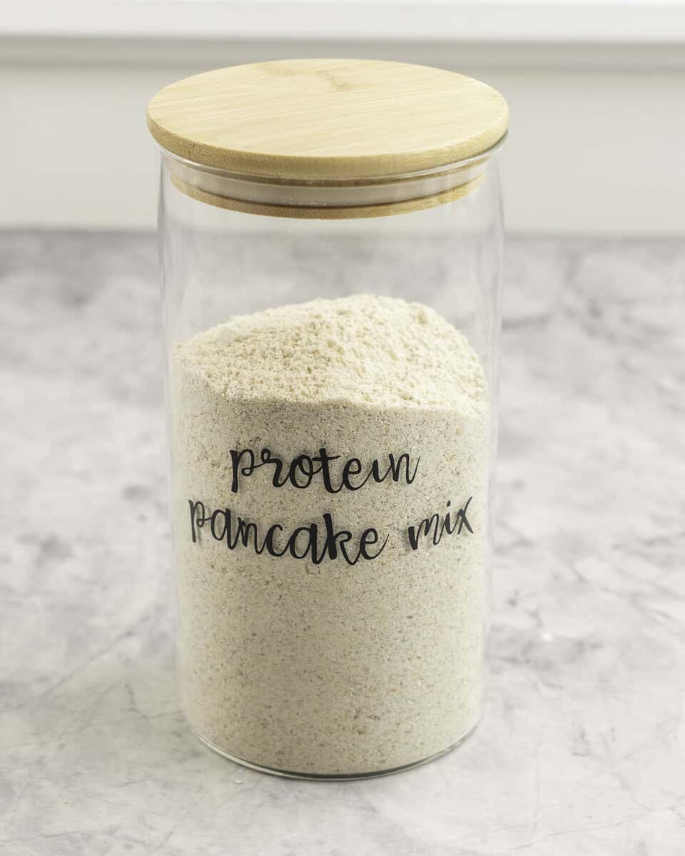 Tall glass container labelled "protein pancake mix" filled with pancake mix.