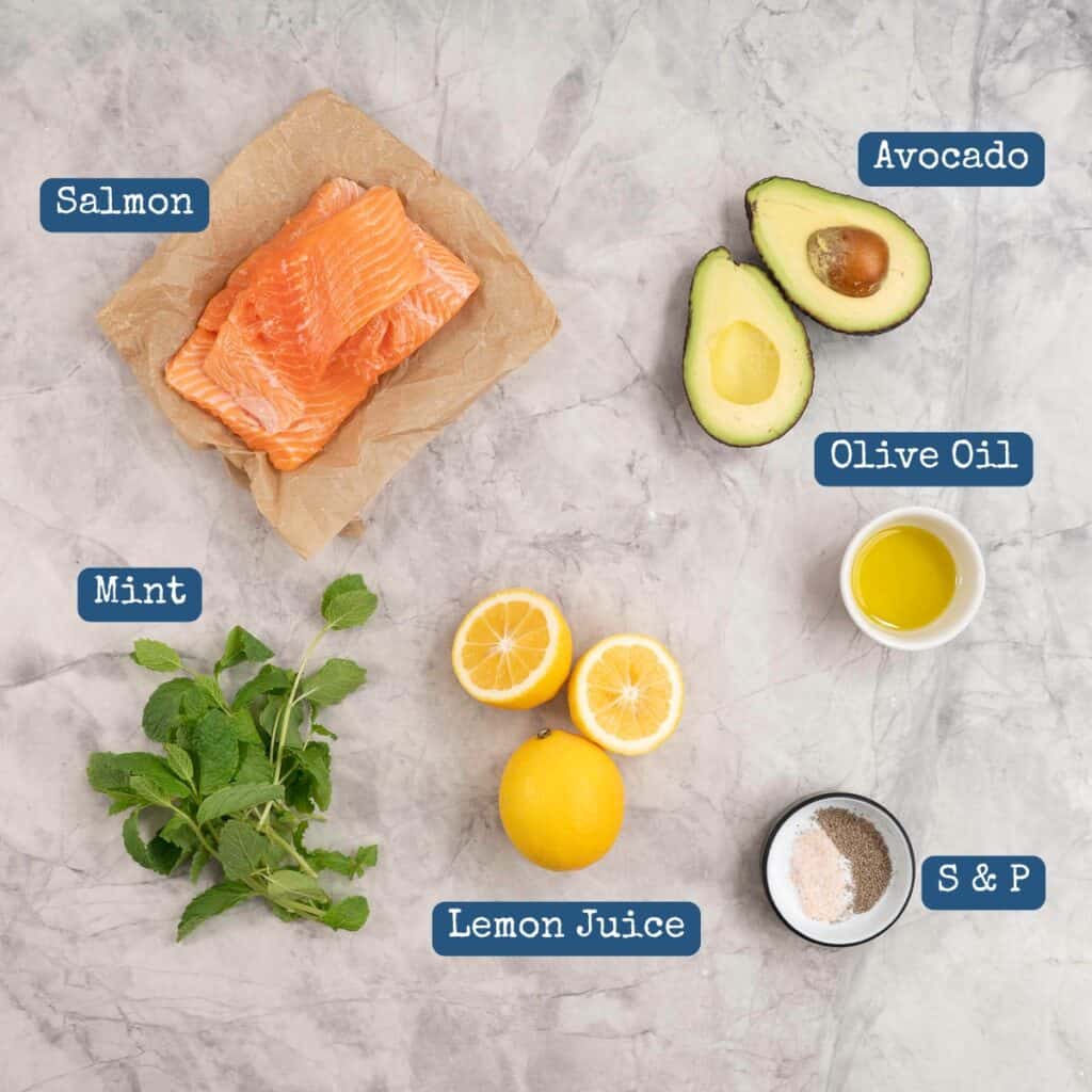 Salmon, avocado, lemons and mint leaves on a bench top with text overlay. 