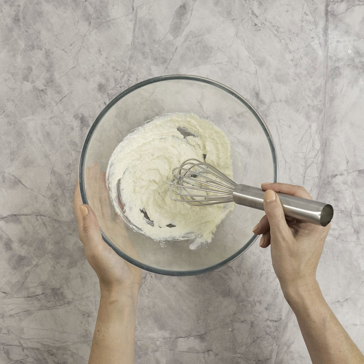 Yogurt based caesar salad being made in the bottom of a large glass bowl. 
