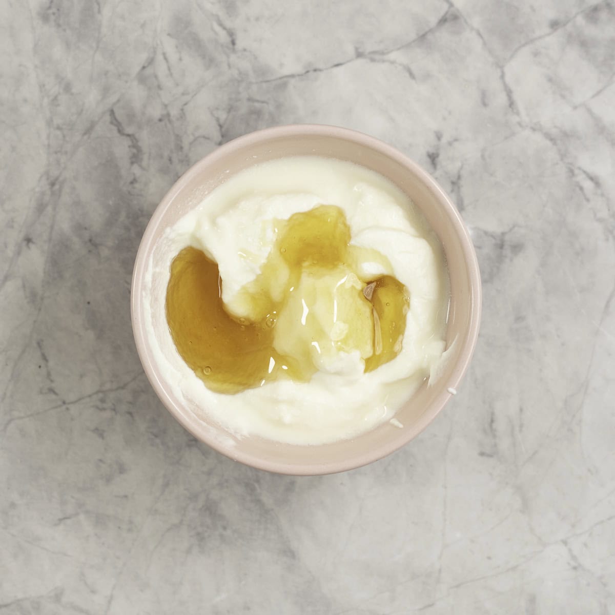 A small bowl of yogurt with honey drizzled on top.